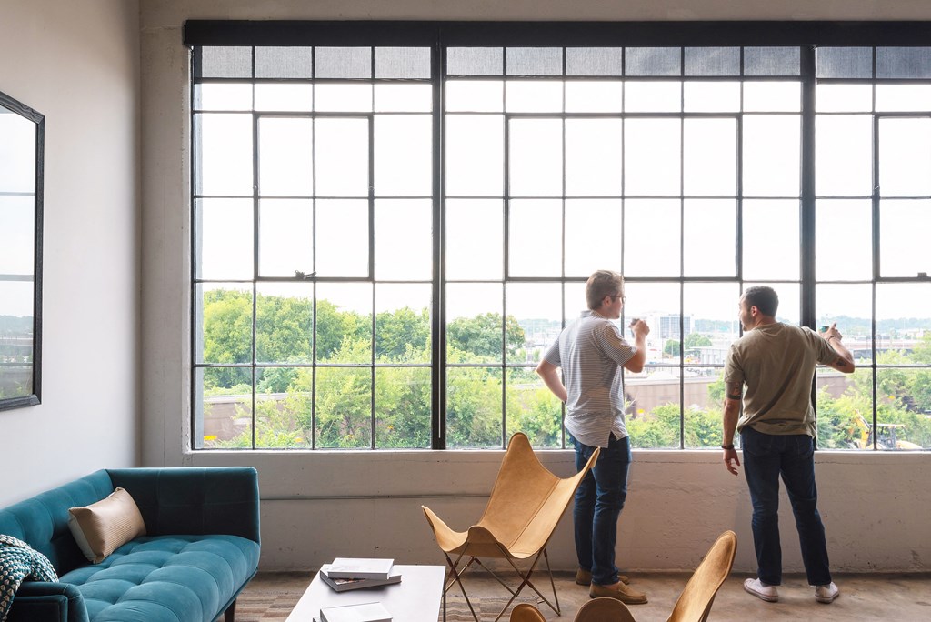 two men standing in front of a large window in a living room